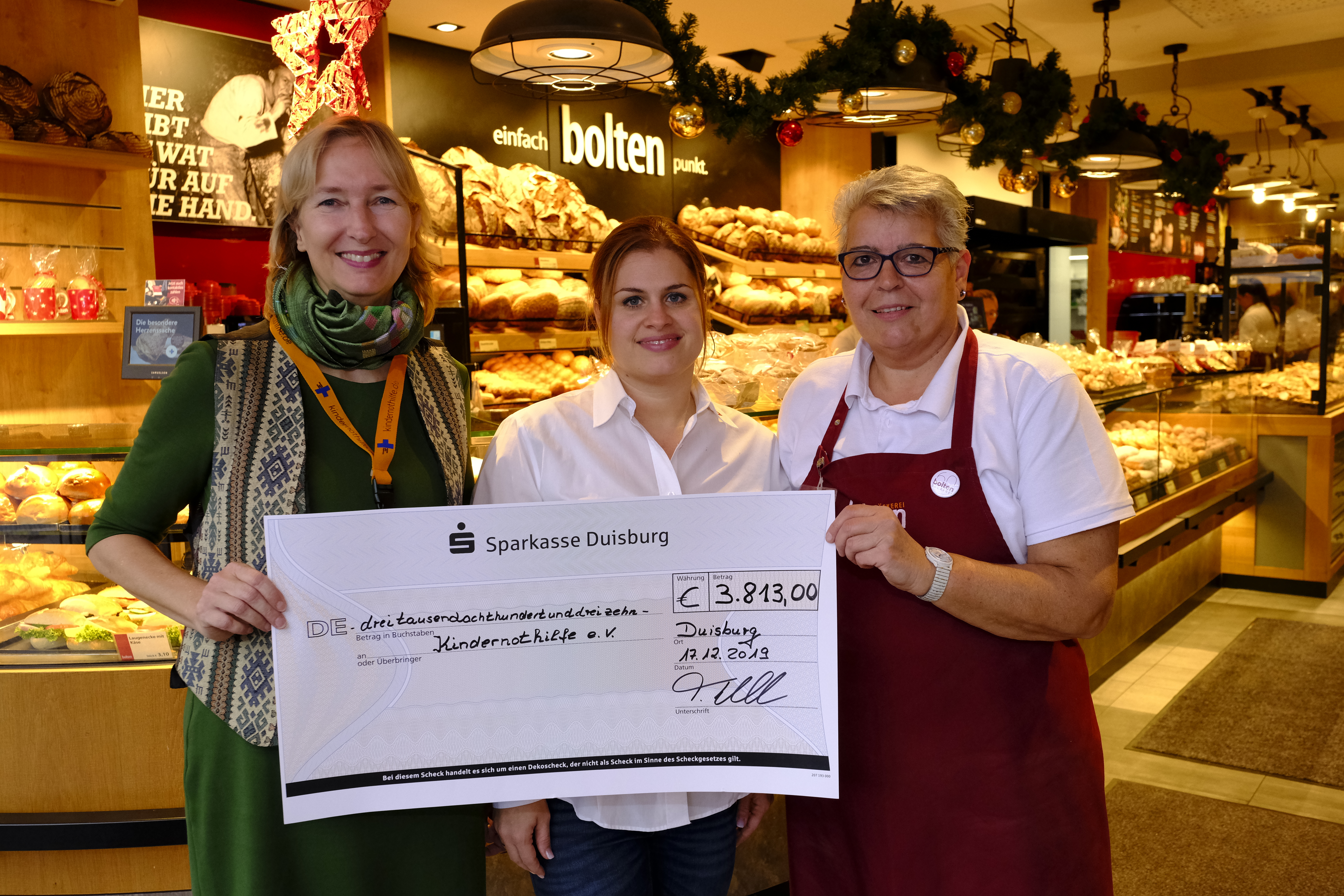 Maite Bolten-Bahr (Mitte), Verkaufsleiterin der Bäckerei Bolten, überreicht Katrin Weidemann (links) den Scheck über 3.813 Euro. Rechts: Claudia Steinke, Filialleiterin der Bäckerei Bolten auf der Königstraße (Quelle: Martin Bondzio).