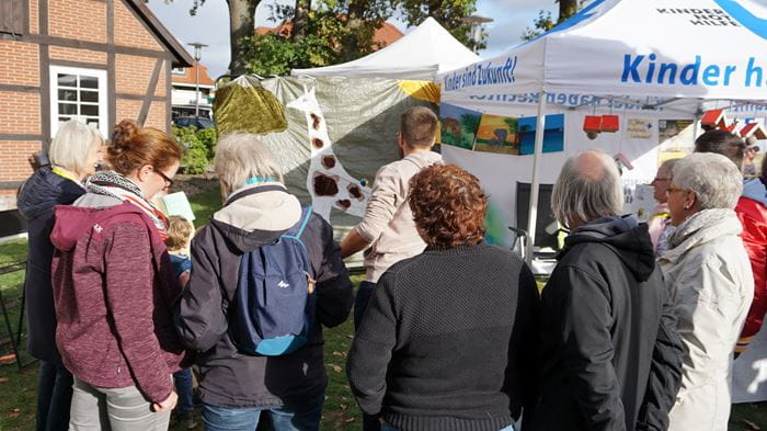 Reportage "Ein Dorf in Kindernothilfe-Hand"; Foto: Menschen vor Stand des Arbeitskreises Lachendorf (Quelle: Ralf Krämer / Kindernothilfe)