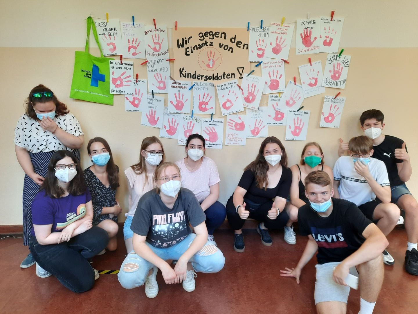 Die Schülerinnen und Schüler posieren vor ihren gesammelten Roten Händen gegen den Einsatz von Kindersoldaten.