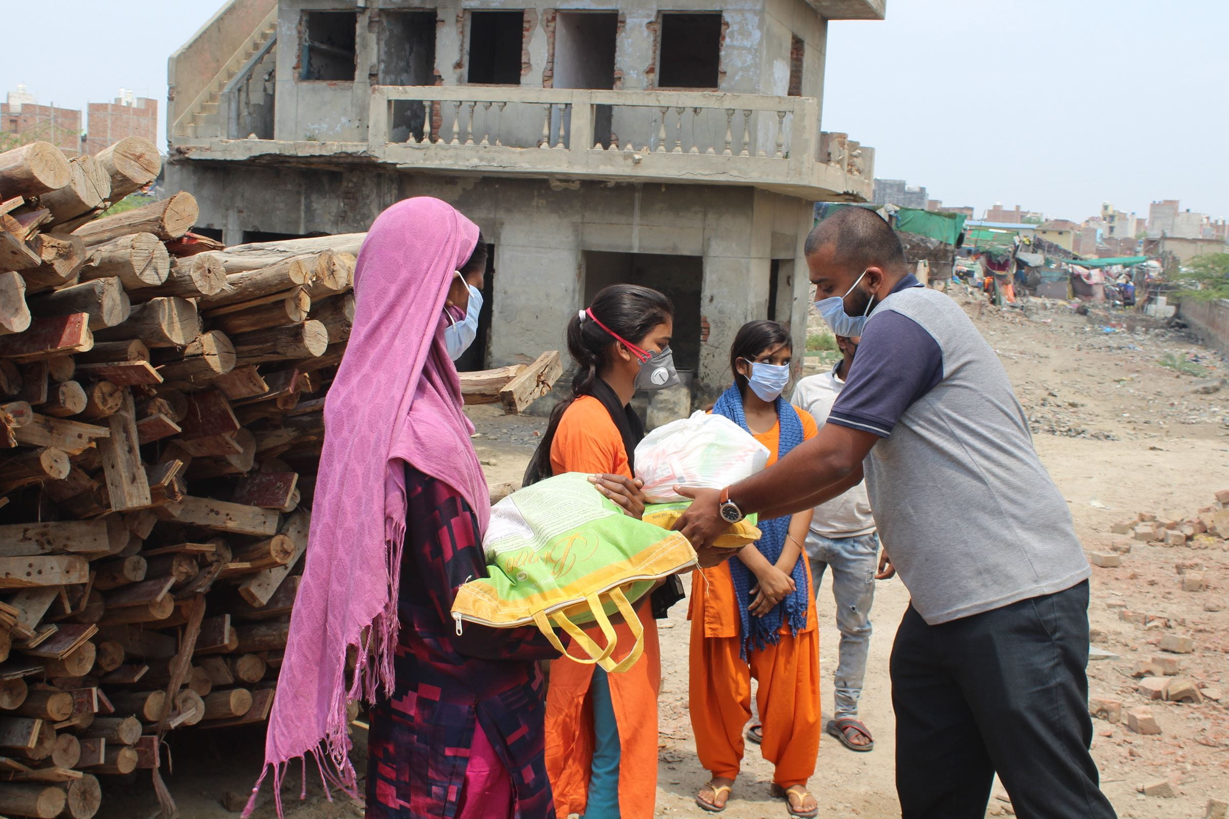 Ein Projektmitarbeiter in Indien verteilt Lebensmittel an Frauen. (Quelle: Kindernothilfe-Partner)