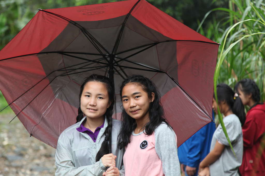 Zwei Mädchen in Thailand stehen unter einem Regenschirm. (Quelle: Christian Herrmanny)