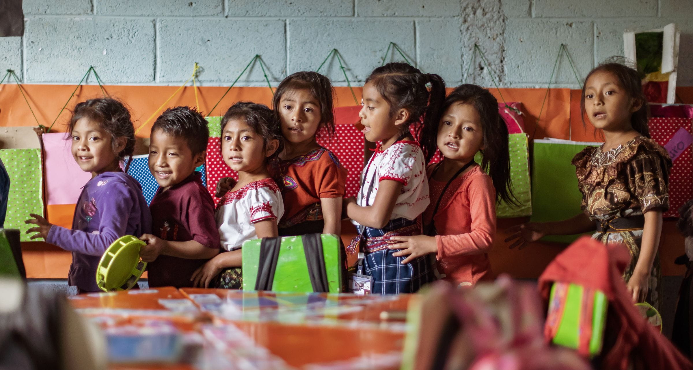 Kinder aus Guatemala stehen hintereinander in einem bunten Klassenzimmer. (Quelle: Jakob Studnar)