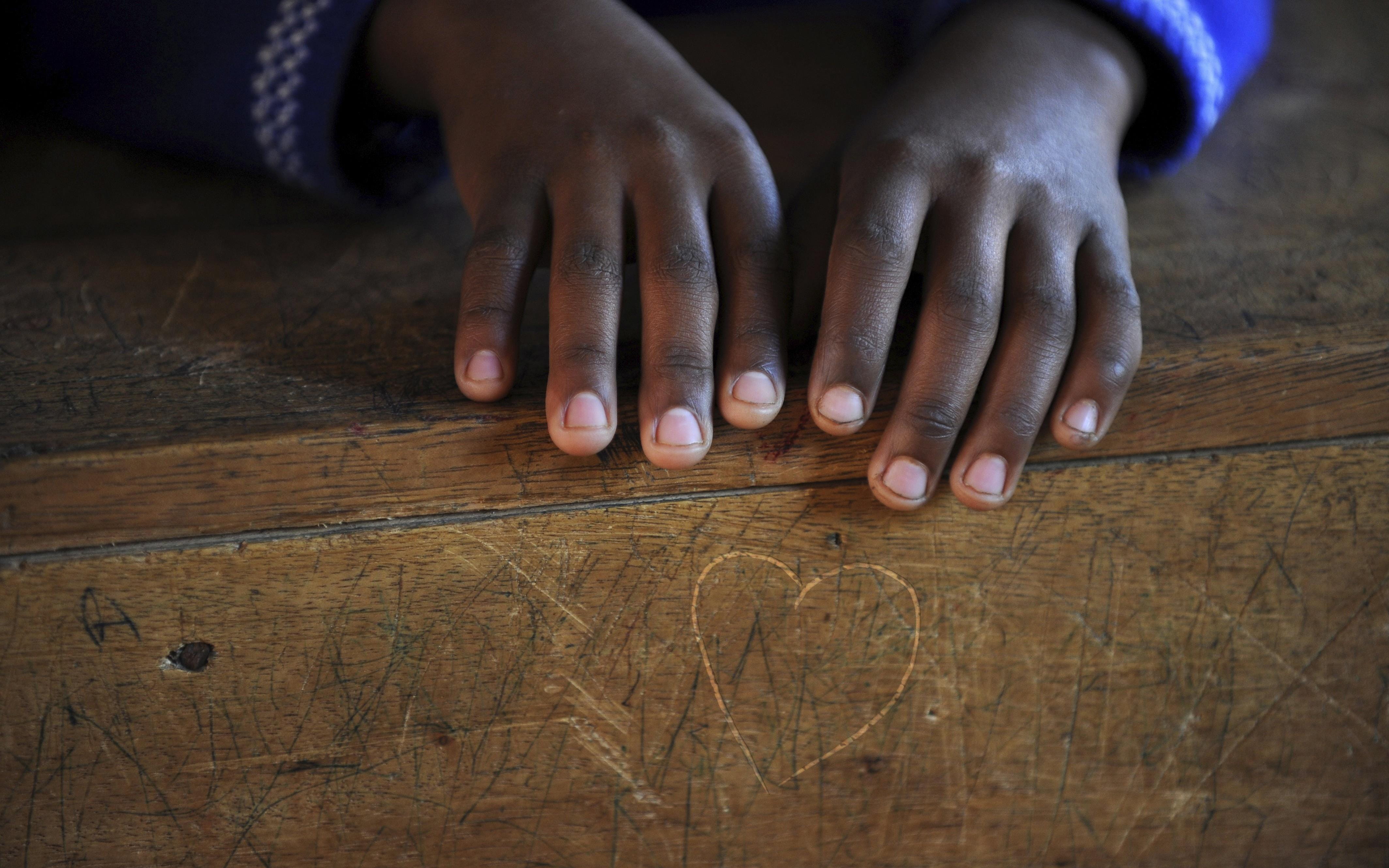 Coverfoto des Flyers "Testamente für die Kindernothilfe"; Kinderhände auf Schulbank (Quelle: Alexander Volkmann /Kindernothilfe)