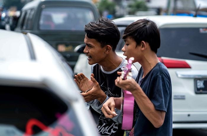 Zwei Straßenmusiker singen und spielen vor einem offenen Autofenster (Quelle: Lennart Zech)