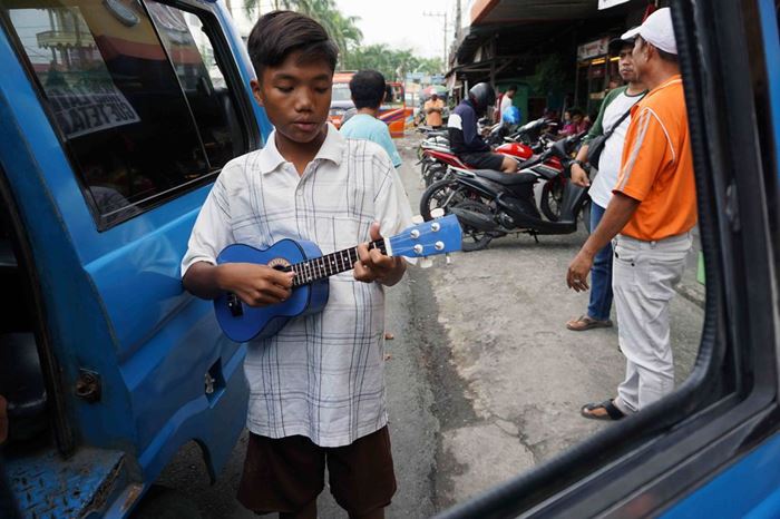 Ein Junge mit einer Gitarre vor einem offenen Autofenster (Quelle: Christiane Dase)