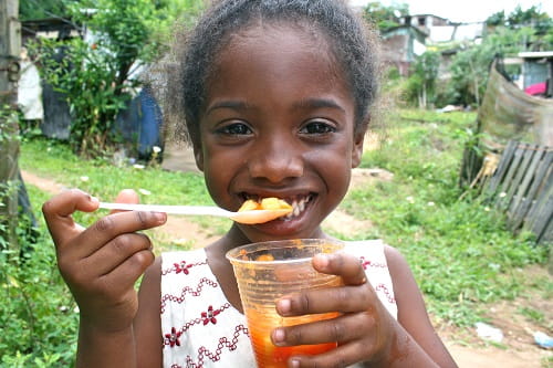 Mädchen strahlt hinter einer Portion Essen (Foto: Jürgen Schübelin)